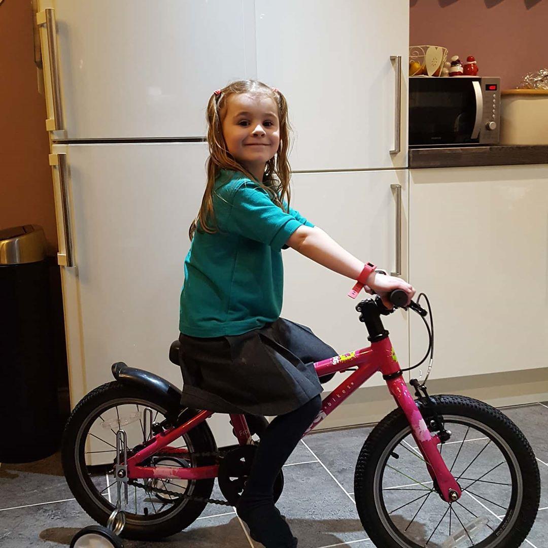 young girl sitting on a bike with stabilisers on in her kitchen, taken by Instagram account @Dalehall2810